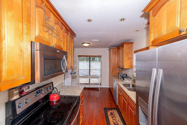 kitchen featuring appliances with stainless steel finishes, sink, dark wood-type flooring, and light stone counters