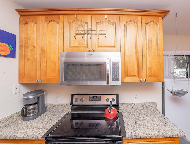 kitchen with appliances with stainless steel finishes and light stone counters