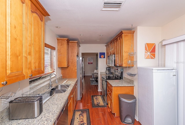 kitchen with appliances with stainless steel finishes, sink, and dark wood-type flooring