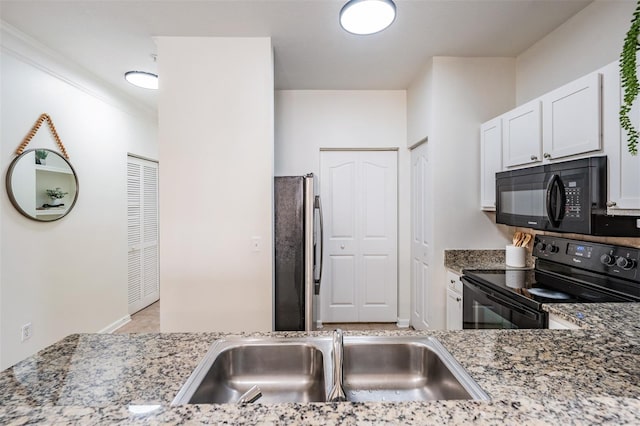 kitchen featuring light stone counters, white cabinets, sink, and black appliances