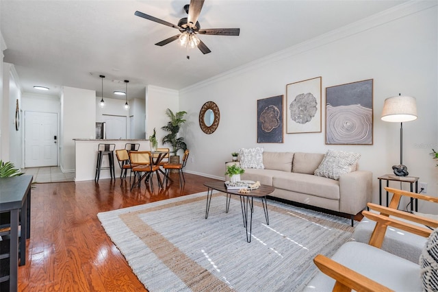 living room featuring crown molding, dark wood-type flooring, and ceiling fan