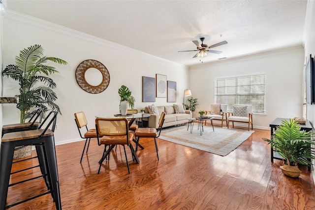 living room with ceiling fan, ornamental molding, hardwood / wood-style floors, and a textured ceiling