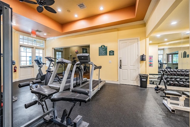 gym featuring crown molding, ceiling fan, plenty of natural light, and a tray ceiling