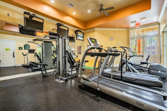 exercise room featuring ceiling fan, ornamental molding, and a tray ceiling