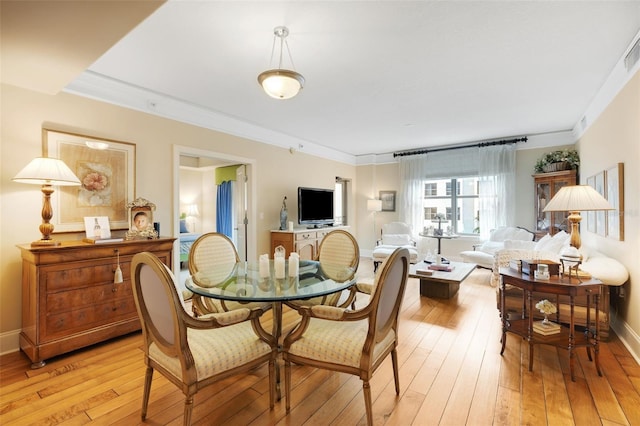 dining space featuring crown molding and light wood-type flooring