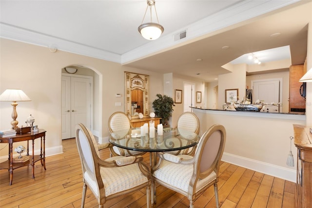 dining area with crown molding and light hardwood / wood-style flooring