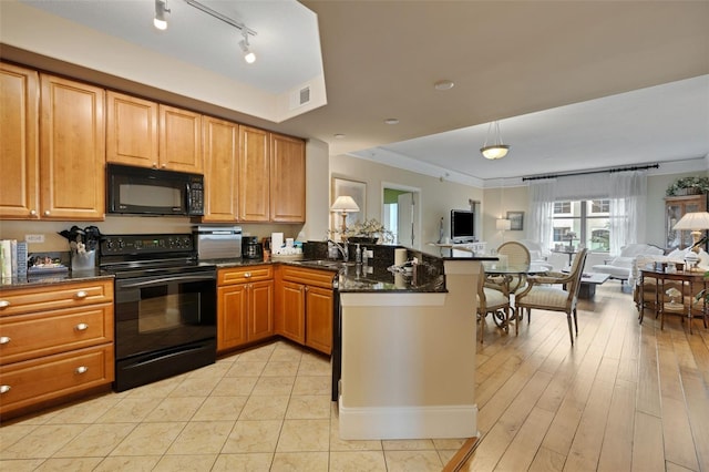 kitchen featuring sink, light wood-type flooring, kitchen peninsula, dark stone counters, and black appliances