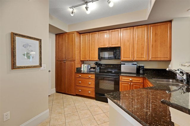 kitchen with sink, black appliances, dark stone counters, and light tile patterned flooring