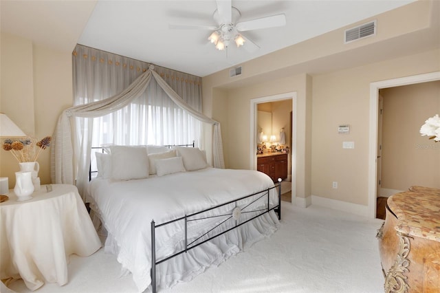 bedroom featuring ceiling fan, ensuite bath, and light carpet