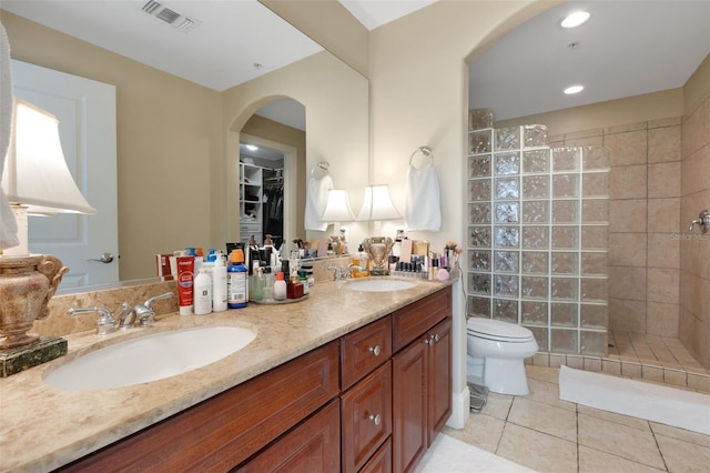 bathroom featuring vanity, tiled shower, tile patterned floors, and toilet