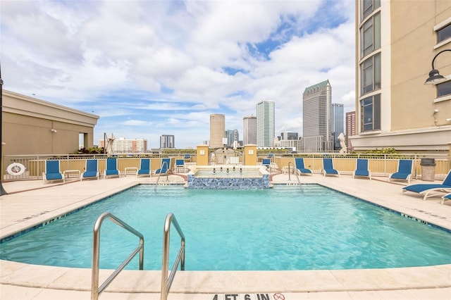 view of swimming pool featuring a hot tub and a patio area