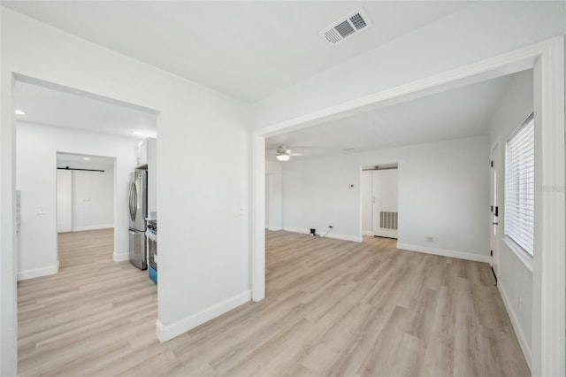 unfurnished living room featuring ceiling fan, a barn door, and light hardwood / wood-style floors