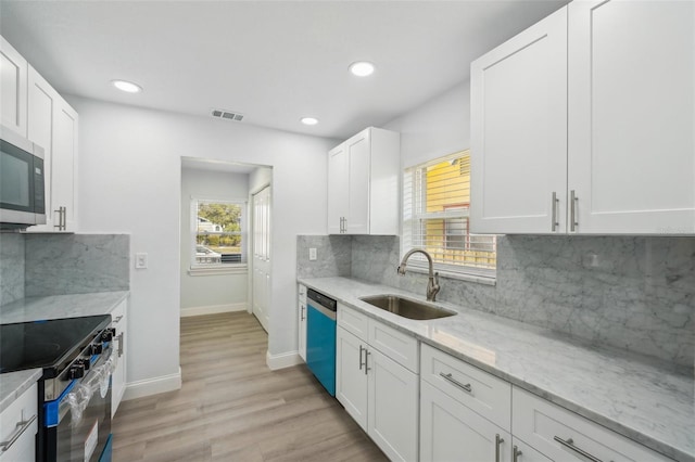 kitchen featuring sink, white cabinets, stainless steel appliances, light stone countertops, and backsplash