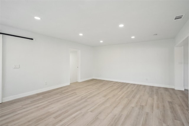 unfurnished room featuring a barn door and light wood-type flooring