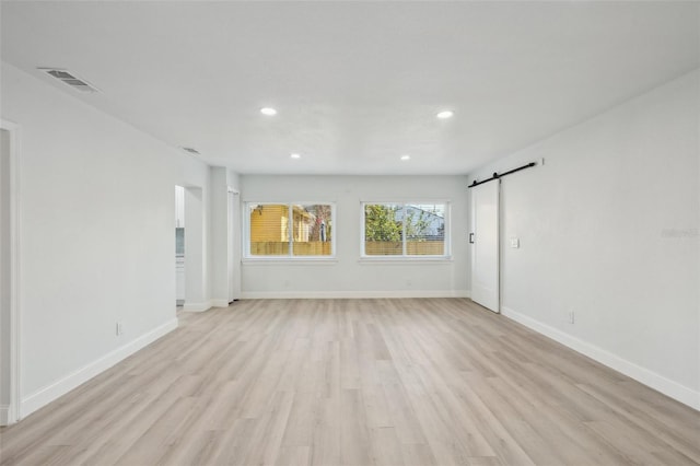 spare room featuring a barn door and light wood-type flooring