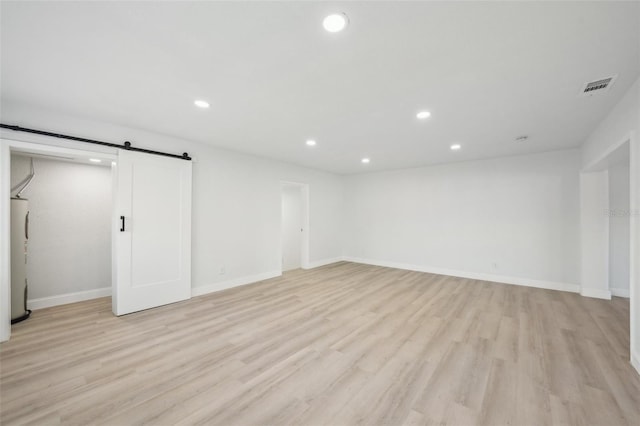 interior space with a barn door, electric water heater, and light hardwood / wood-style flooring