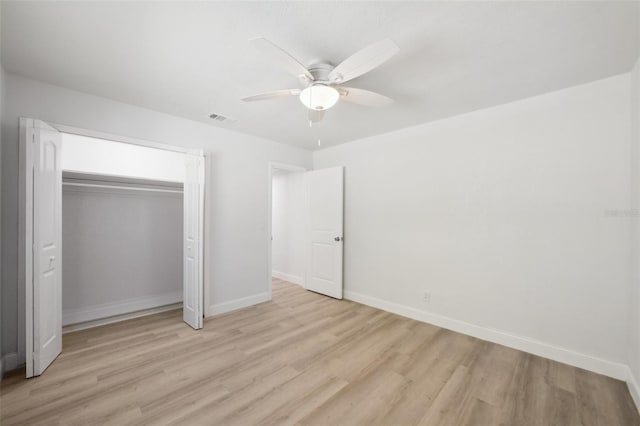 unfurnished bedroom with light wood-type flooring, ceiling fan, and a closet