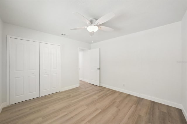 unfurnished bedroom with light wood-type flooring, ceiling fan, and a closet