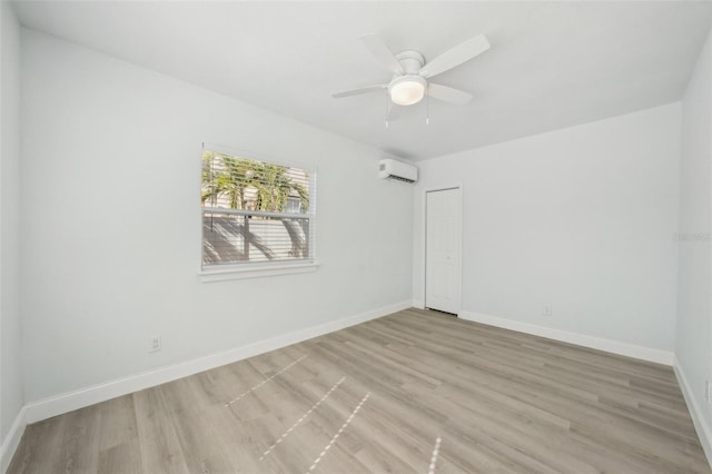 empty room featuring ceiling fan, a wall mounted AC, and light hardwood / wood-style flooring