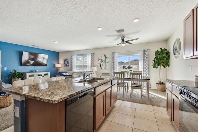 kitchen featuring sink, stainless steel range with electric cooktop, light carpet, dishwasher, and an island with sink