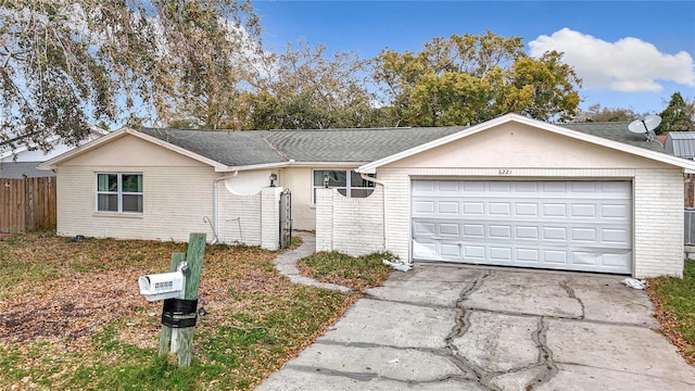 single story home with an attached garage, driveway, fence, and brick siding