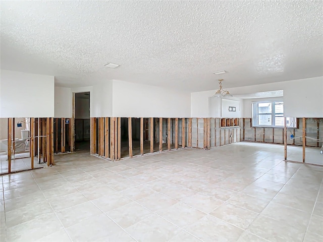 unfurnished room with a wainscoted wall, light tile patterned floors, and a textured ceiling