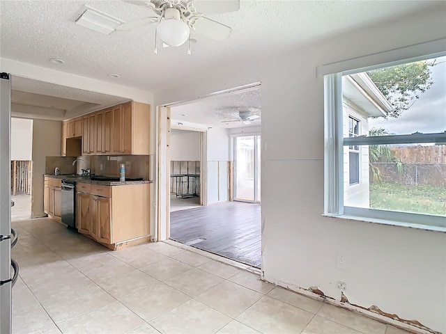 kitchen with dishwasher, dark countertops, a textured ceiling, light brown cabinets, and light tile patterned flooring