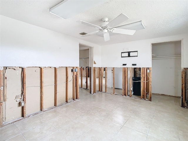 empty room featuring visible vents, ceiling fan, and a textured ceiling