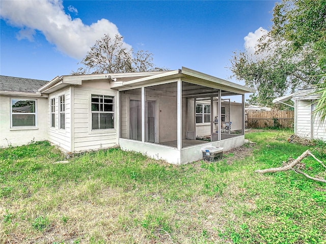 back of property featuring a sunroom, fence, and a lawn