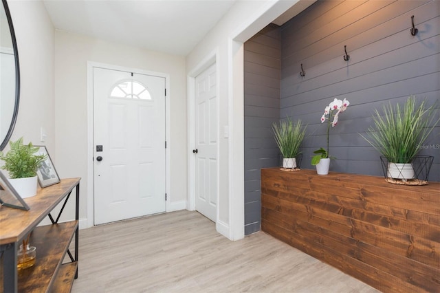 foyer entrance with wooden walls and light wood-type flooring