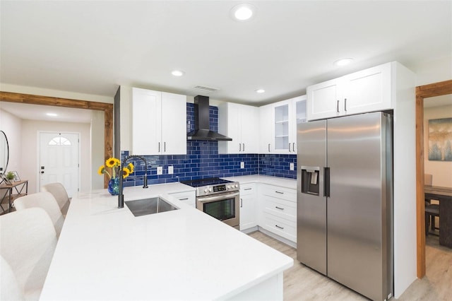 kitchen featuring sink, light hardwood / wood-style flooring, stainless steel appliances, white cabinets, and wall chimney exhaust hood