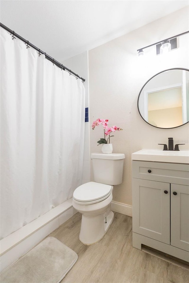 bathroom with a shower with curtain, wood-type flooring, vanity, and toilet