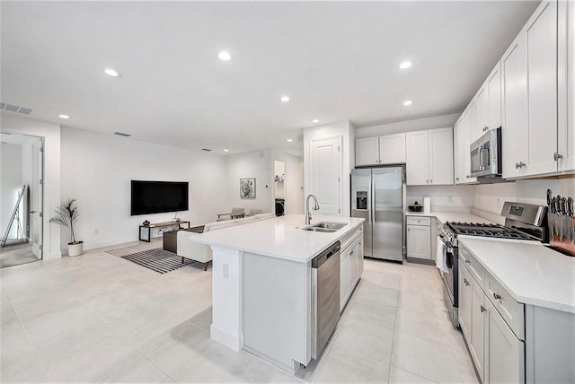 kitchen with light tile patterned flooring, sink, white cabinetry, a center island with sink, and stainless steel appliances