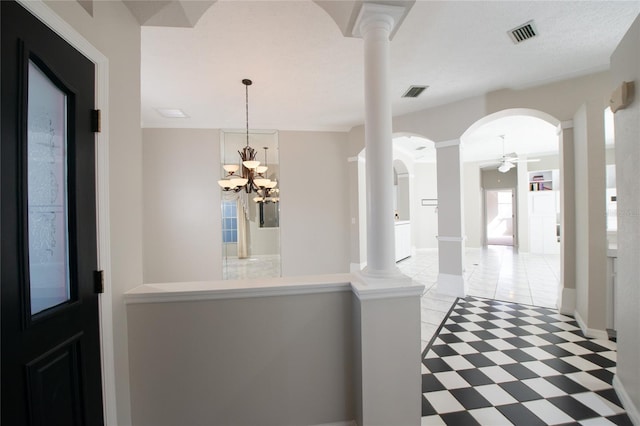 foyer entrance with decorative columns, ceiling fan with notable chandelier, and a textured ceiling