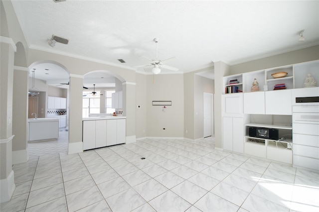 unfurnished living room featuring ornamental molding, light tile patterned floors, a textured ceiling, and ceiling fan