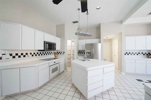 kitchen with decorative light fixtures, an island with sink, sink, white cabinets, and stainless steel appliances