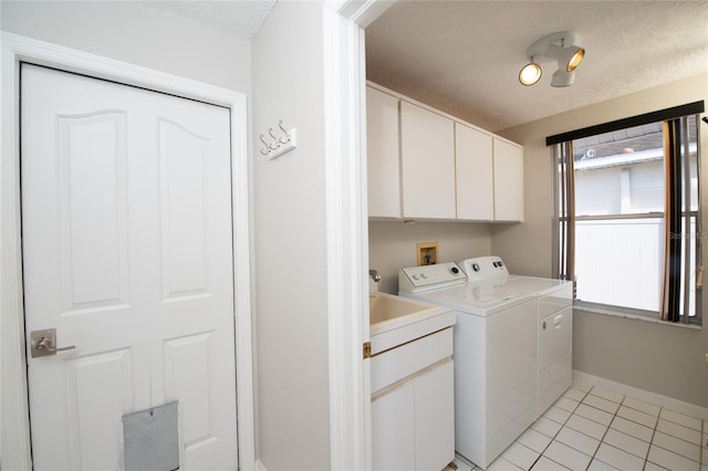 washroom featuring cabinets, light tile patterned flooring, a textured ceiling, and washer and clothes dryer