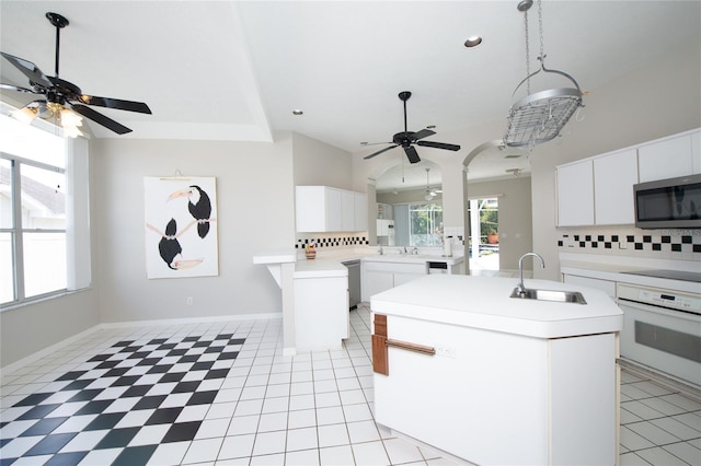 kitchen featuring white cabinets, an island with sink, sink, and oven