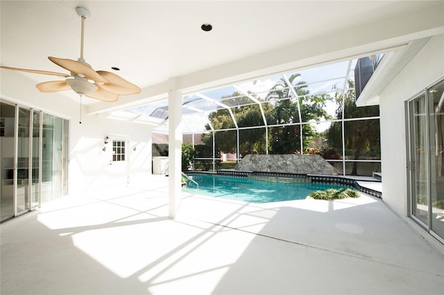 view of pool with a patio, ceiling fan, and glass enclosure