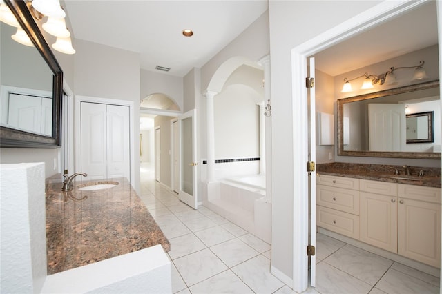 bathroom featuring tiled tub, vanity, tile patterned flooring, and ornate columns