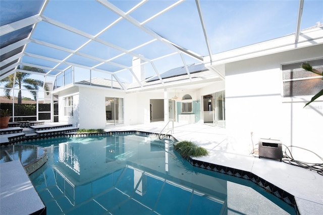 view of pool with a jacuzzi, glass enclosure, and a patio area