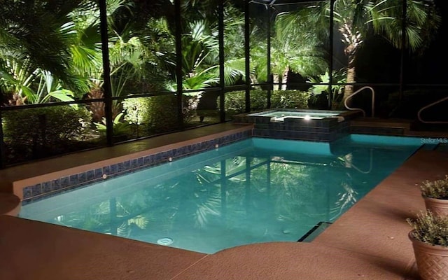 pool featuring glass enclosure and an in ground hot tub