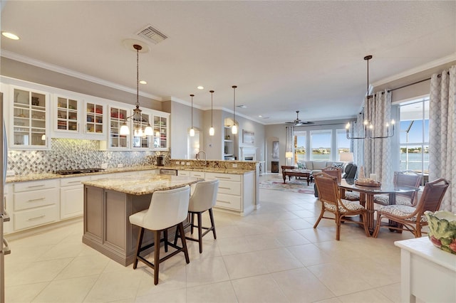 kitchen with a kitchen island, decorative light fixtures, white cabinets, a kitchen bar, and decorative backsplash