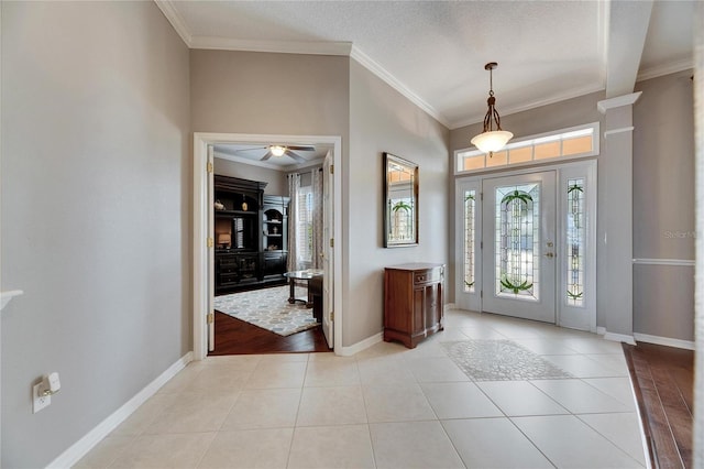 tiled entrance foyer featuring crown molding, a healthy amount of sunlight, and a textured ceiling