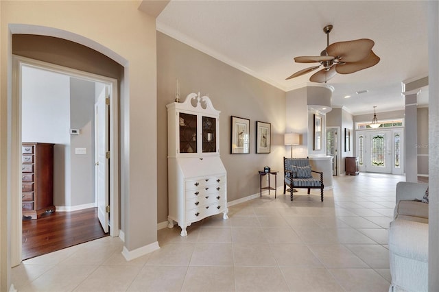 living room with crown molding, light tile patterned floors, and ceiling fan