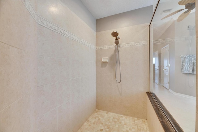 bathroom with ceiling fan and tiled shower