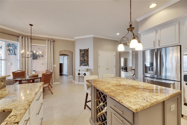 kitchen with white cabinetry, light stone countertops, pendant lighting, and stainless steel fridge