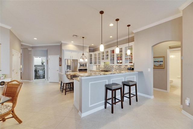 kitchen featuring pendant lighting, kitchen peninsula, tasteful backsplash, and white cabinets