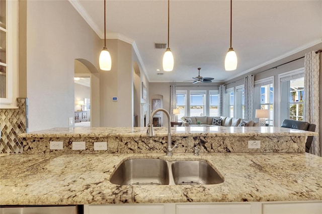 kitchen featuring pendant lighting, ornamental molding, sink, and plenty of natural light