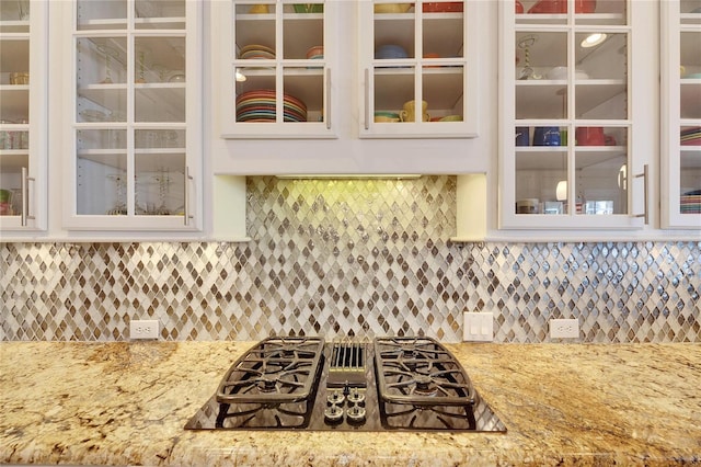 kitchen with light stone countertops, decorative backsplash, and black gas cooktop